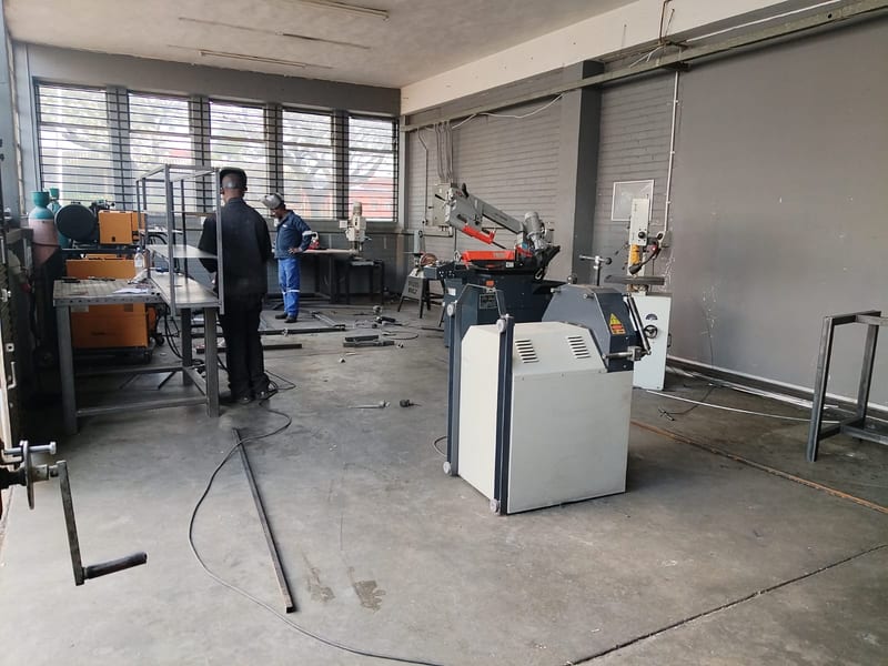 Metal fabrication bay with a cutting bandsaw, drill press, and welding equipment